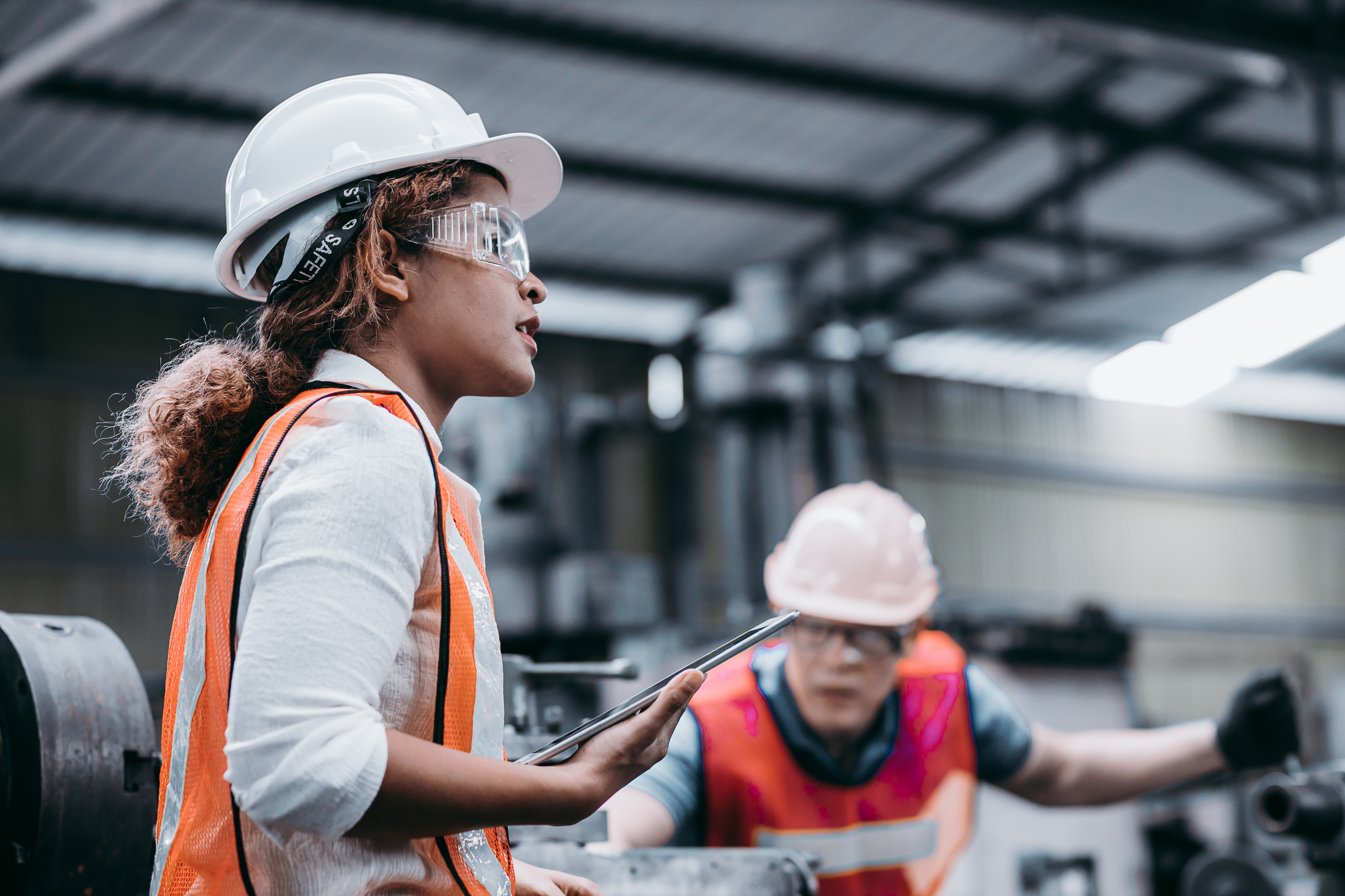 Female technician performing inspection on heavy excavator in construction operation